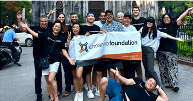 Photo de groupe extérieure montrant des membres de la Fondation Armanino en train d'applaudir et brandissant une banderole Armanino.