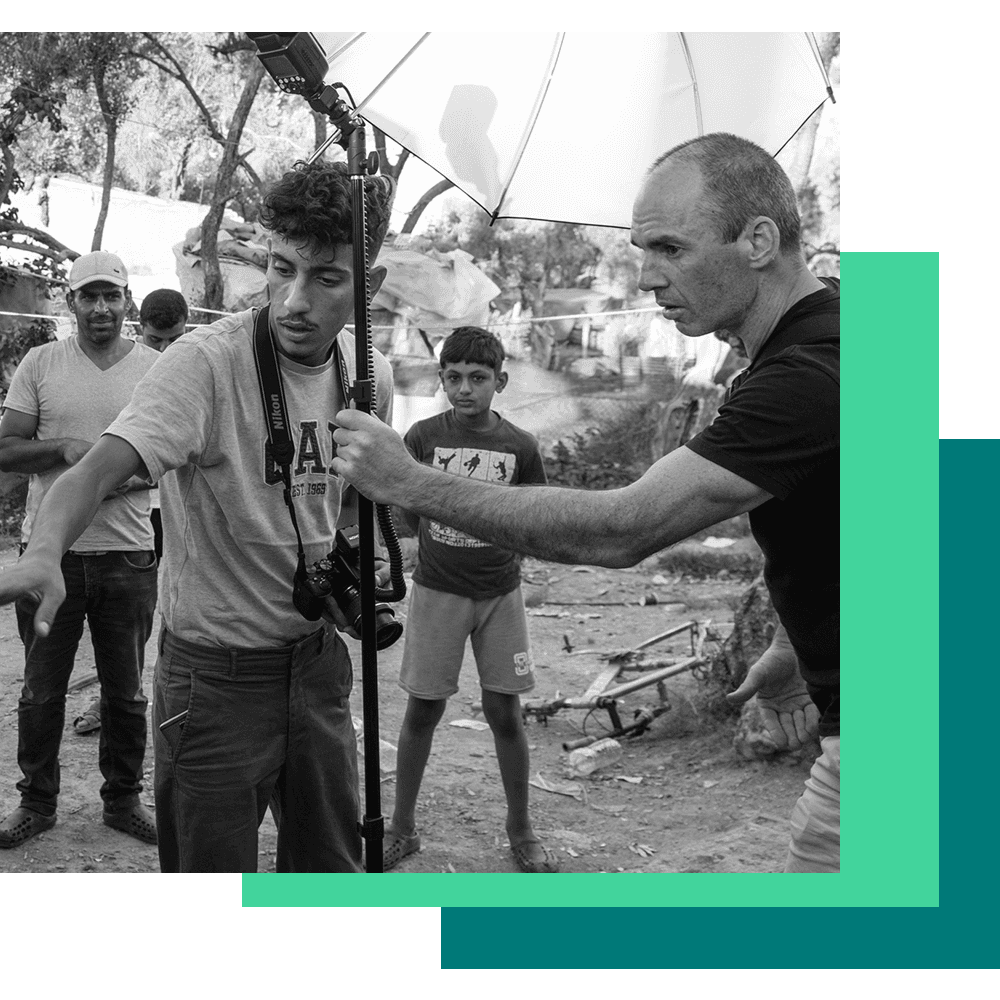 um fotógrafo está sendo ajudado por seu assistente a tirar fotos de refugiados